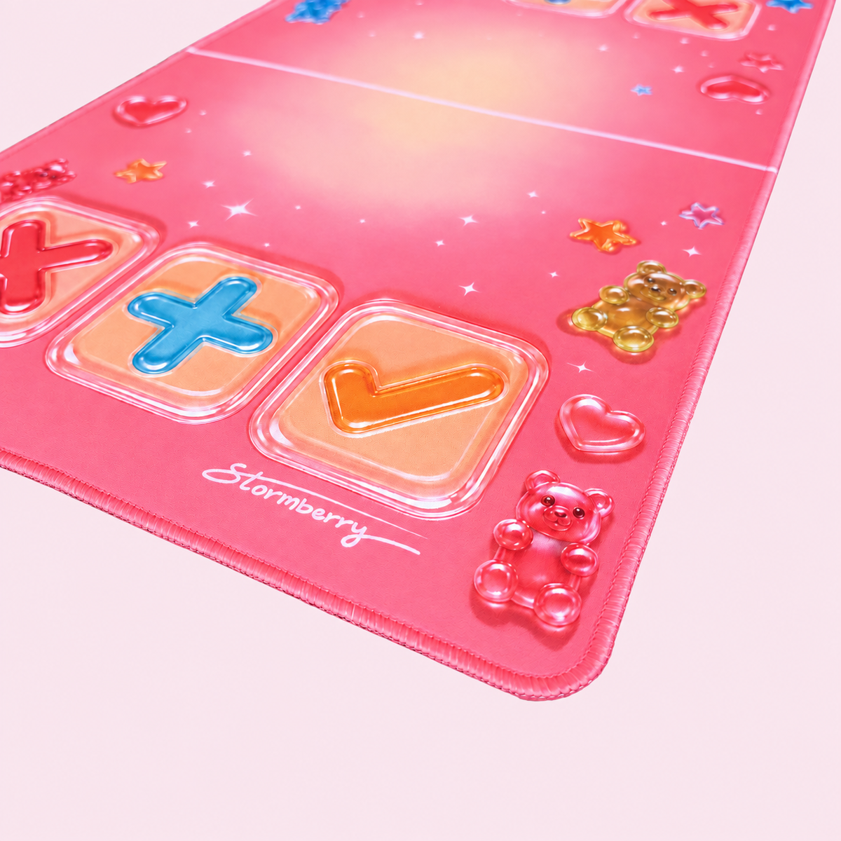 Close-up of the Gummy Gloss mat's printed gummy bears, blue plus, orange check and pink stitched edge.