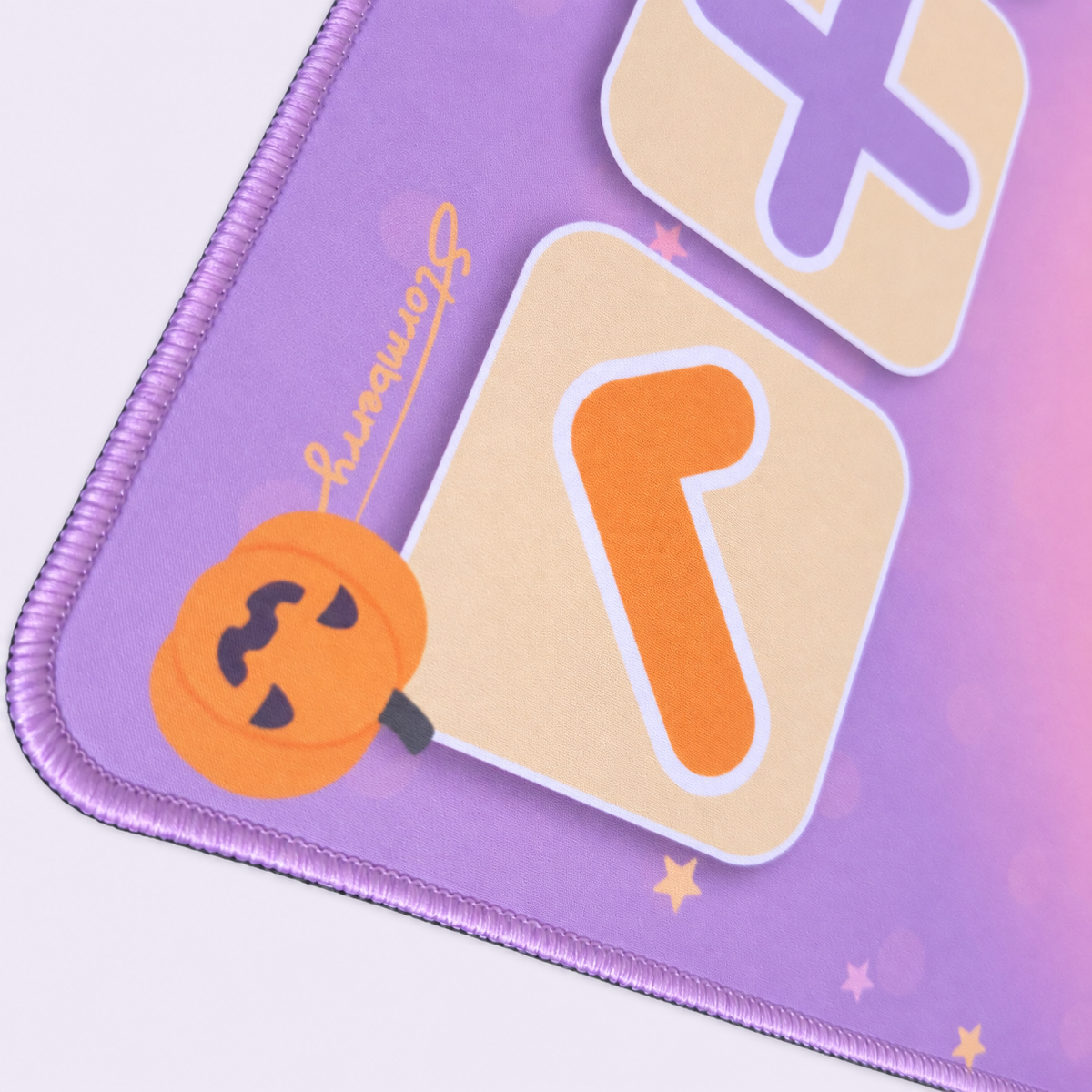 Close up of the Pastel Halloween mat's orange pumpkin, orange check, printed logo and lavender stitching.