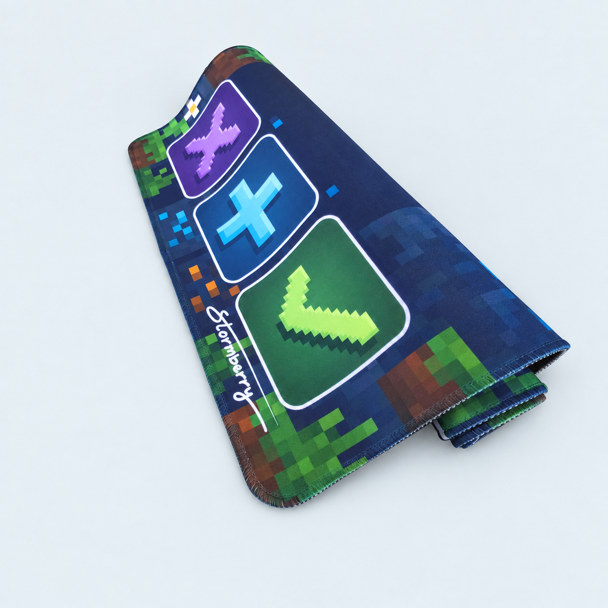 Rolled Pixel Block trading mat with stitched edges, green and brown pixel blocks and three colorful trading symbols.